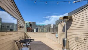 A rooftop patio with a table and chairs, a street lamp, and a view of buildings in the background. - Beautiful, Modern Pet-Friendly Downtown Executive Rental (Denver)