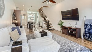 A spacious living room with a modern staircase, a flat-screen TV, and a ceiling fan. - Beautiful, Modern Pet-Friendly Downtown Executive Rental (Denver)