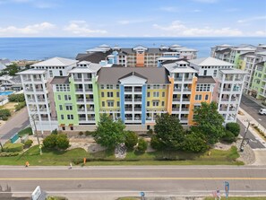 A multi-story hotel with balconies, a swimming pool, and a view of the ocean. - Book Sandtastic Penthouse 421A | Sandbridge Vacation Rental (Virginia Beach)