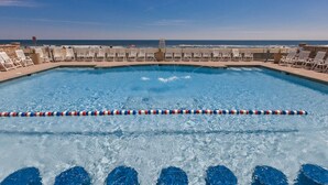 A swimming pool with a view of the ocean, surrounded by lounge chairs and a lifeguard tower. - Book Sandtastic Penthouse 421A | Sandbridge Vacation Rental (Virginia Beach)