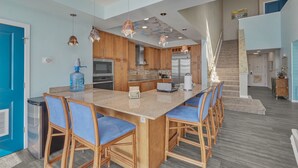 A spacious kitchen with a large island, wooden cabinets, and modern appliances. - Book Sandtastic Penthouse 421A | Sandbridge Vacation Rental (Virginia Beach)