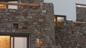 A modern building with stone walls and large windows. - Calma Suites Mykonos (Mykonos)