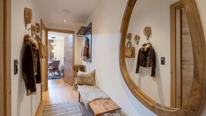 A hallway with a wooden bench, a round mirror, and coats and bags hanging on the wall. - Landhaus Dengg in Gerlos: Rosengarten Apartment for 2 to 4 people (Gerlos)