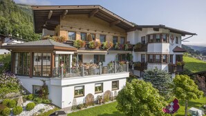 A two-story chalet with a balcony, a garden, and a view of the mountains. - Landhaus Dengg in Gerlos: Rosengarten Apartment for 2 to 4 people (Gerlos)