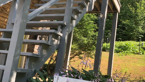 Una scala di legno conduce a un pontile con un cartello che recita 'Between the Pines'.