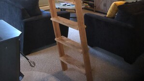 Una stanza in stile loft con una scala in legno, due divani scuri, una televisione e un tavolino.