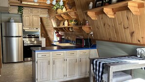 Una cucina con mobili in legno, un frigorifero in acciaio inossidabile, un forno a microonde e un lavandino.
