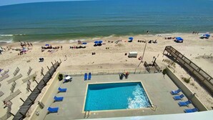 A beach view with a swimming pool, sun loungers, and umbrellas. - Beachfront, Pool & Sunroom (Gulf Shores)