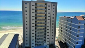A high-rise hotel with multiple balconies, a beach view, and a parking area. - Beachfront, Pool & Sunroom (Gulf Shores)