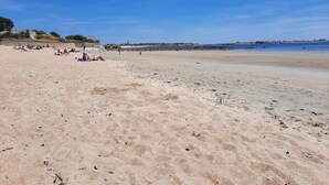 A wide sandy beach with a clear blue sky.