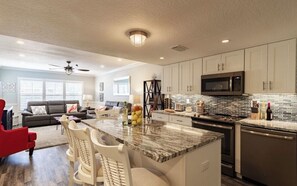 A modern kitchen with white cabinets, a granite countertop, and stainless steel appliances. - Spectacular Views of Beach and Bay (Longboat Key)