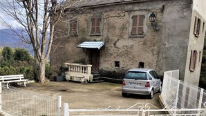 A stone building with a car parked in front, a white fence, and a bench. - Village house 20 minutes from the beach (Piedicroce)