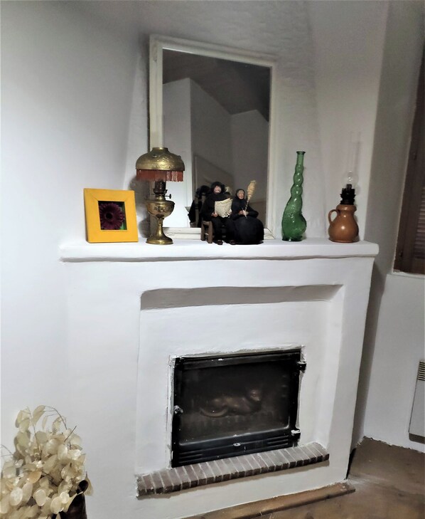 A white fireplace with a mirror above it, a yellow picture frame, a brass lamp, and decorative items on the mantel. - Village house 20 minutes from the beach (Piedicroce)