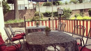 An outdoor seating area with a round table and chairs, covered by umbrellas, and a small potted plant on the table. - Hotel-Restaurant Zum Karpfen (Obernburg)