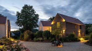 A house with a cobblestone driveway, a garden with flowers, and a bench. - Büchelbergerei Chaletdorf (Gunzenhausen)