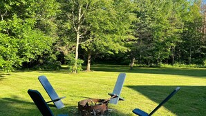 A grassy outdoor area with a fire pit and four lounge chairs. - House minutes from Pymatuning Lake! (Jamestown)