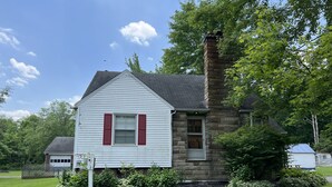 A two-story house with a stone chimney, white siding, and red shutters. - House minutes from Pymatuning Lake! (Jamestown)