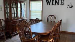A dining room with a wooden table and chairs, a wooden cabinet, a ceiling fan, and a window with blinds. - House minutes from Pymatuning Lake! (Jamestown)