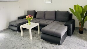 Una sala de estar moderna con un sofá modular, una pequeña mesa blanca y una planta en maceta.