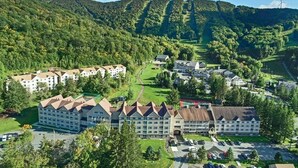 A hotel complex with multiple buildings, surrounded by lush greenery and hills.
