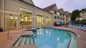 A hotel with a swimming pool, lounge chairs, and a building with large windows.