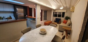 Une cuisine moderne dotée d’un réfrigérateur encastré et d’un coin repas avec une table et des chaises en marbre.