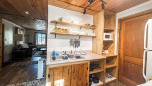 Eine kleine Küche mit Holzausstattung, einer Spüle und einer Mikrowelle.