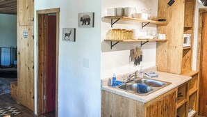 Eine Küche mit Holzausstattung, einer Spüle und Regalen mit Geschirr und Besteck.