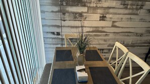 Una mesa de comedor con cuatro individuales negros, un florero con plantas secas y una caja de pañuelos.