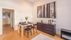 Un salon moderne avec une table à manger en bois, des chaises noires, un buffet en bois foncé et un grand tableau abstrait accroché au mur.