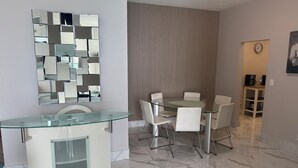 Une salle de bain moderne avec un lavabo entouré de parois en verre, un miroir au motif géométrique et un rideau à rayures.