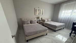 Une chambre avec deux lits, un sol en marbre, une table de chevet, une lampe et un tableau au mur.