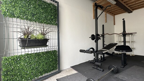 A gym with a weight bench, squat rack, and barbell. - Villa Pópulo 5 min. from the beach (ponta delgada)