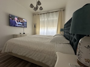 A bedroom with a bed, a television on the wall, a bedside table, and a lamp.