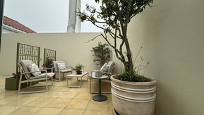 A patio with outdoor furniture, a potted plant, and a decorative fence. - Villa Pópulo 5 min. from the beach (ponta delgada)
