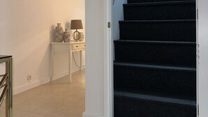 A staircase leading to an upper floor, a small table with a lamp, and a white wall. - Villa Pópulo 5 min. from the beach (ponta delgada)