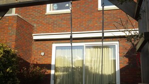 Een bakstenen huis met terras, schommel en een schuifdeur.