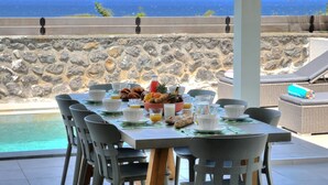 A dining table set with breakfast items and a view of the ocean.