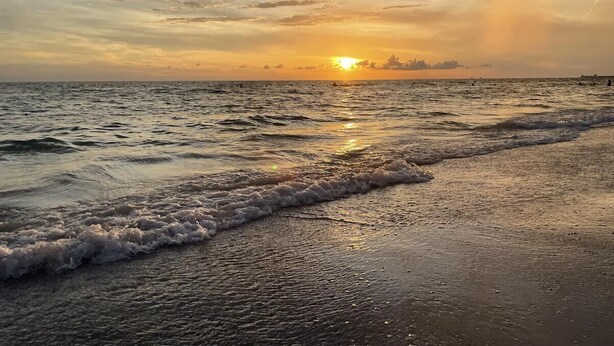 A beach with waves at sunset.