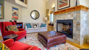 A living room with a fireplace, red armchairs, a white sofa, and a patterned rug. - Extraordinary Stratton Ski On/Ski Off Home (Stratton)