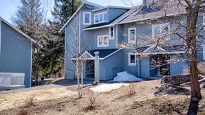 A two-story house with a blue exterior and a garage. There is a small driveway with a gravel path leading to the garage. - Extraordinary Stratton Ski On/Ski Off Home (Stratton)
