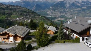 Un pueblo de montaña con casas de madera tradicionales y un edificio moderno con estacionamiento.