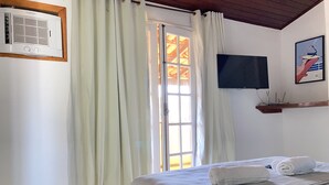 Una camera d'albergo con un letto, una televisione a parete e una finestra con tende.
