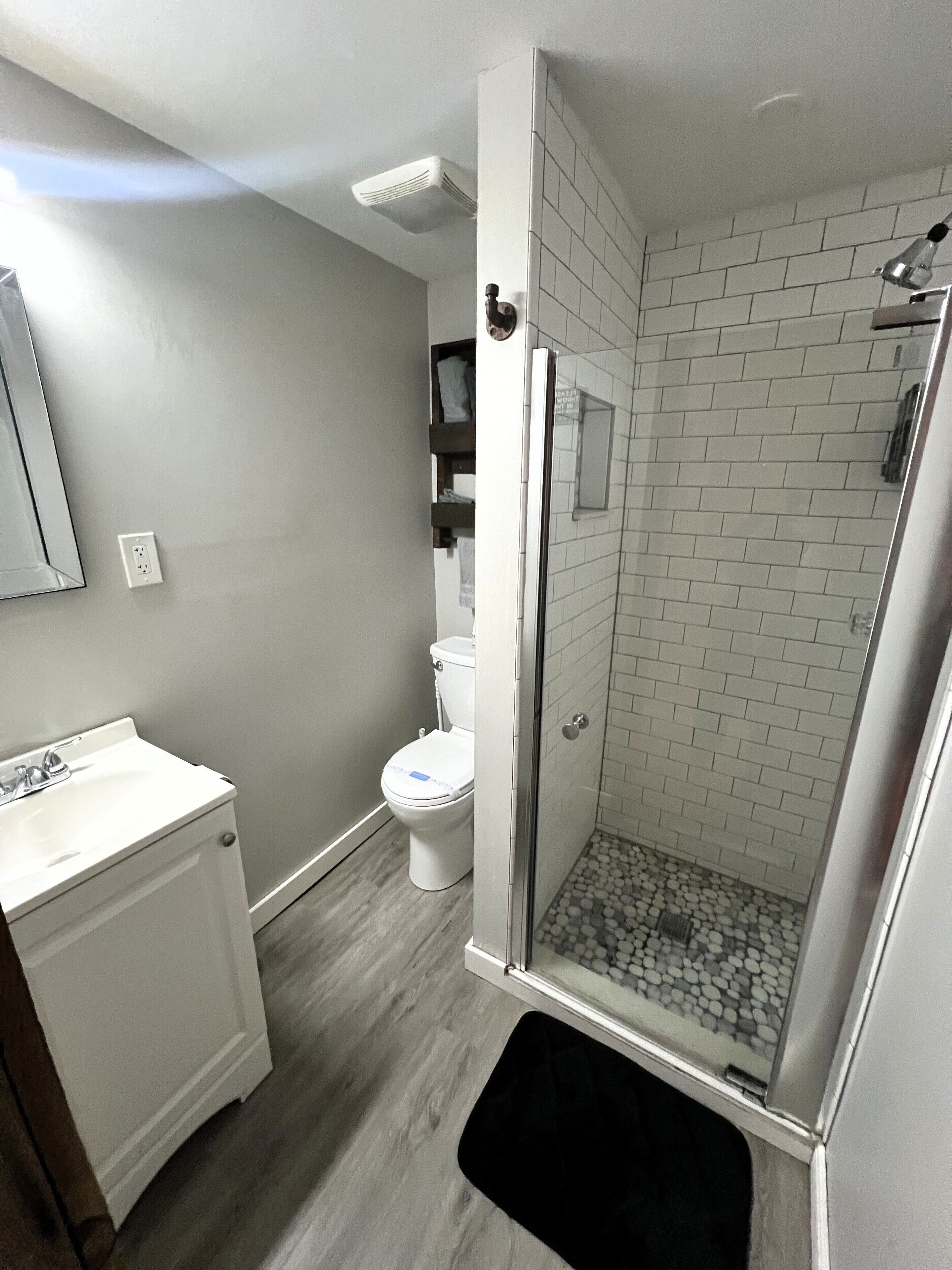 Ein modernes Badezimmer mit bodengleicher Dusche, Toilette und Waschbecken.