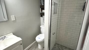 Ein modernes Badezimmer mit bodengleicher Dusche, Toilette und Waschbecken.