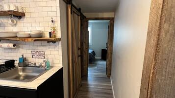 A kitchen with a sink, wooden cabinets, and a sign instructing not to leave dishes in the sink.