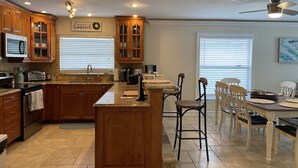 A kitchen with wooden cabinets, a central island, and a dining area with chairs.
