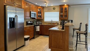 A modern kitchen with wooden cabinets, stainless steel appliances, and a central island with bar stools.