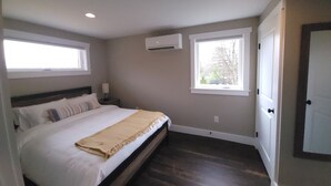 Een slaapkamer met een bed, twee ramen, een airconditioning en een deur.
