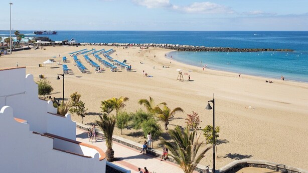 A beach with rows of blue umbrellas, a sandy shore, and a clear blue sea. - Home2Book Sunny Apt Pool & Terrace, Las Américas (Playa de la Américas)